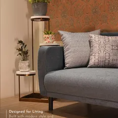 This setting showcases how I pair different elements for a cohesive look. The modern blue sofa is complemented by a rust-toned designer wallpaper and a tiered marble plant stand, creating a warm and inviting corner that is full of character.