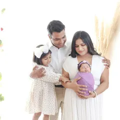 A bright and airy family portrait celebrating the new addition. This image captures the joy of a growing family, with the older sibling gently welcoming the new baby.