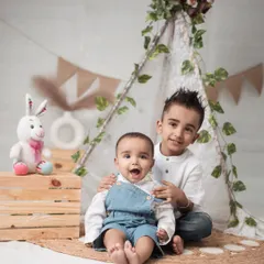 The bond between siblings is a story I love to tell. In this cozy teepee setup, the older brother’s gentle hold and the baby’s wide-eyed wonder create a heartwarming scene. I aim to capture these unposed, tender interactions that show the real connection within a family.
