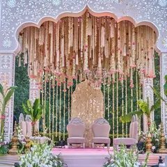 This mandap was a vision of romance, with a canopy of hanging florals, a traditional gold backdrop, and lush banana leaves, all in a soft palette of pink and ivory for a daytime wedding.