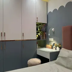A smart space-saving solution in a kid's room in Jasola. The wardrobe incorporates a built-in study nook with a desk and open shelving for books.