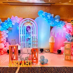 A vibrant and sweet candyland themed birthday stage. This colorful setup features inflatable ice cream and donut props, pastel balloon arches, and a whimsical gate backdrop.