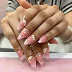A delicate and intricate 3D floral design. These long, pink-tipped nails are adorned with tiny white flowers, silver glitter lines, and scattered rhinestones for a fairy-tale look.