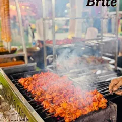 Skewers of bright red chicken tikka being expertly grilled over hot coals. The intense heat chars the meat perfectly, locking in the marinade and creating an irresistible smoky flavor.
