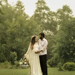 A sweet, candid moment from an outdoor picnic-themed shoot. The hat and basket of flowers add a lovely, rustic touch.