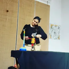A smiling moment during a puppet show at an art gallery. The artwork on the walls adds to the creative atmosphere of the performance.