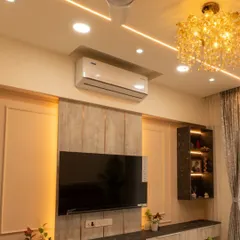 The living room of the Pune home, featuring a minimalist TV unit with integrated lighting and storage.