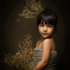 A stunning fine art portrait of a young girl. The moody lighting, earthy tones, and her direct gaze create a powerful and artistic image.