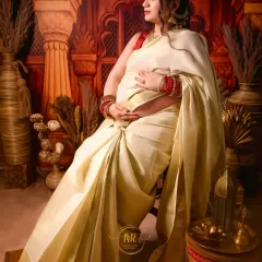 An elegant portrait of an expectant mother in a classic white and gold Kasavu saree. The simplicity and grace of the attire are captured beautifully in this seated pose.