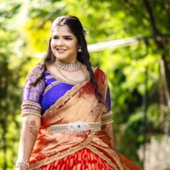 A client glowing in her bespoke engagement half saree. The vibrant red and blue Kanjivaram fabric creates a stunning traditional look, customized to make her feel special on her big day.