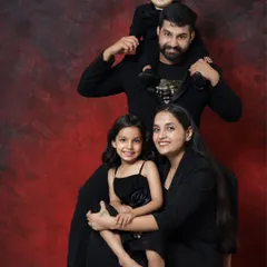 A classic family portrait with a creative pose. The father with his son on his shoulders, and the mother with her daughter, creates a beautiful, balanced, and loving image.