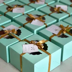 Elegant return favours for a naming ceremony. These beautiful sea-green boxes with a window are tied with a gold ribbon and a custom tag to thank guests for their blessings.
