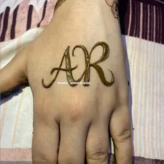The initials 'AR' are the star of this design, drawn in a flowing script on the back of the hand.