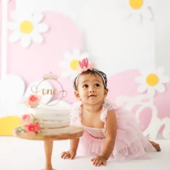 Getting ready to dive in. This shot captures the moment of anticipation right before the cake smash begins, with the birthday girl crawling towards her beautiful first birthday cake.