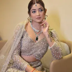 A seated portrait of the same party look, showing how the makeup looks from a different angle. The winged eyeliner and soft hairstyle create an elegant and modern vibe.