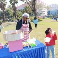A child delighted with a fresh stick of cotton candy at an outdoor park event. The candy floss machine is always a visual and tasty attraction.