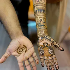 A special couple's mehendi for an engagement. The bride-to-be has a full narrative design, while the groom-to-be has their initials in a simple crest on his palm.