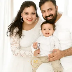 A bright and happy family portrait with both parents and their baby boy, all dressed in white. I always encourage parents to join in, as these moments of connection are truly priceless.