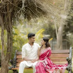 A serene portrait of the couple sitting on a park bench, dressed in traditional Maharashtrian attire. The natural setting complements the simplicity and elegance of their look.