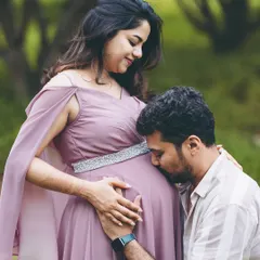 A classic and tender pose. The partner's gentle kiss on the belly is a timeless expression of love and excitement for the new arrival, captured during an outdoor couple's maternity session.