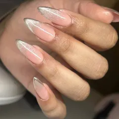 A glamorous twist on the French manicure. This design features a sheer nude base with a sparkling silver cat-eye effect on the tips of these long, stiletto-shaped nails.