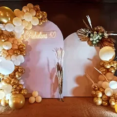"Fabulous 50" indeed! This modern and chic setup uses two arched backdrops, a beautiful gold and white balloon garland, and dried floral elements for a sophisticated look.