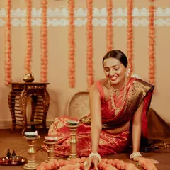 A candid shot of a woman arranging a circle of marigold flowers and diyas on the floor, her smile capturing the simple joys of preparing for Diwali.