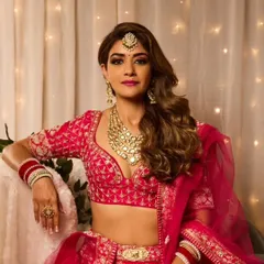 This full-length view shows how the hair and makeup come together with the entire bridal outfit. The glamorous waves add a touch of modern elegance to the traditional attire.