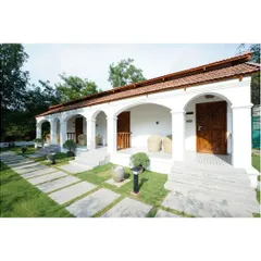 This perspective highlights the relationship between the architecture and the landscape. The clean, geometric lines of the stone pathways guide you through the manicured lawn, leading your eye toward the welcoming, arched verandas. Every element is placed to create a sense of harmony and order.