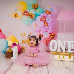 The pure, uncontainable joy of turning one. This little princess is surrounded by a pastel wonderland of donuts and ice cream props.