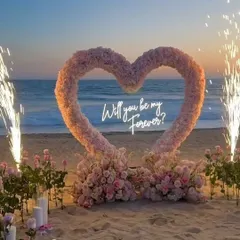 The promise of forever, captured in a single frame. This is a closer look at our signature beach proposal setup, showcasing the lush pink floral heart against the serene ocean backdrop.