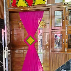 A closer look at a single door decorated with a vibrant pink drape and traditional hangings. This simple addition instantly makes a home entrance feel ready for a celebration.