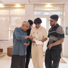 Curator Sarthak and photographer Sridhar Comaravalli engage in a discussion with young visitors during the "Vernissage" exhibition, fostering a dialogue about art.