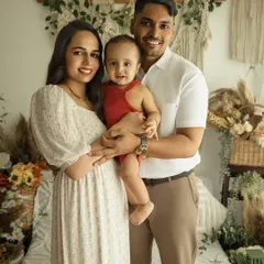 A picture-perfect family of three. This lifestyle portrait captures the family's bright smiles and easy connection in our warm, boho-chic studio setting.