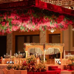 A traditional mandap structure is elevated by a lush ceiling of red and green florals. This design focuses on creating a sacred space that is both grand and intimate, perfect for a heritage wedding.