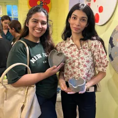 Two happy participants from our hand-building workshop holding up their finished heart-shaped bowls. It is always a joy to see people connect and create together in our studio.