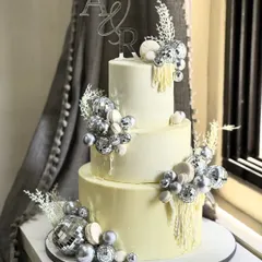 Glamour was the theme for this stunning three-tiered celebration cake. Adorned with sparkling silver disco balls and custom initials, it’s a showstopper designed to make any grand event unforgettable.