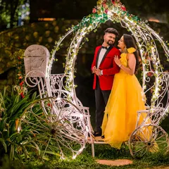A true fairy-tale moment. The couple stands inside a Cinderella carriage adorned with twinkling lights, creating a magical and romantic portrait perfect for any love story.