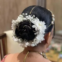 An elegant and clean bridal bun decorated with baby's breath and white chrysanthemums, perfect for a sophisticated look.