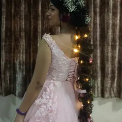 The back view of the pink gown, showing the corset-style tie-up and the beautiful floral and light details in the hair.