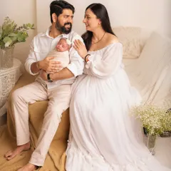 A full-length portrait of a new family relaxing together. The light and airy studio setup with neutral colors creates a calm and peaceful atmosphere.
