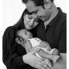 A black and white version of a family portrait can add a timeless, emotional depth. It strips away color to focus purely on the love and connection between the parents and their sleeping newborn.