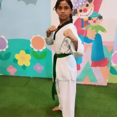 This young green belt is ready for action. Her strong stance and focused gaze show she's prepared for her training.