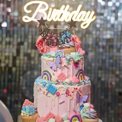 A two-tiered cake for a Candyland themed party. The bottom tier was Chocolate Raspberry and the top was Fresh Fruit, all decorated with candy-colored drips, rainbows, and sweets.