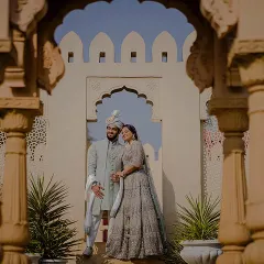 Framed between two pillars, this shot of Yash and Priyanshi offers a beautiful perspective of the couple against a backdrop of classic Indian architecture, creating a sense of depth and grandeur.