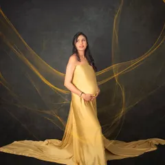 A truly radiant solo portrait of a mom-to-be. The flowing golden gown and ethereal fabric effects create a powerful and elegant image, celebrating the strength and beauty of motherhood.