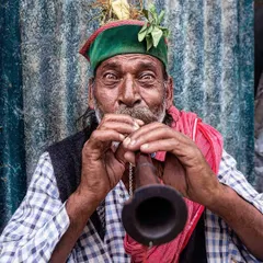 A striking portrait of a street musician playing his instrument, with a direct and engaging gaze that draws the viewer into his world.