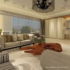 A living room designed for comfort and warmth. The space features plush, neutral-toned sofas, a unique live-edge wood coffee table, and large windows that look out onto a green landscape.