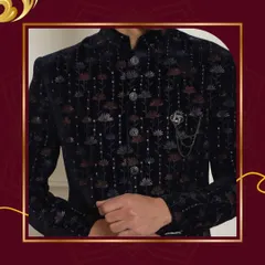 A close-up on a black velvet bandhgala with intricate floral embroidery and a classic brooch. This highlights the detailed craftsmanship that defines our brand.