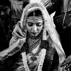 A beautifully composed black and white portrait of a bride in a moment of quiet reflection. The veil and her serene posture give this image a classic, reverent quality.
